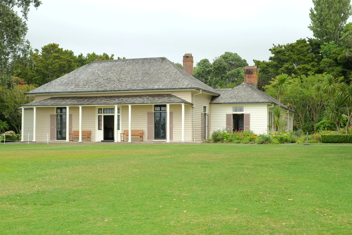 The white weatherboard Treaty House at the Waitangi Treaty Grounds, seen from the front lawn on a clear day